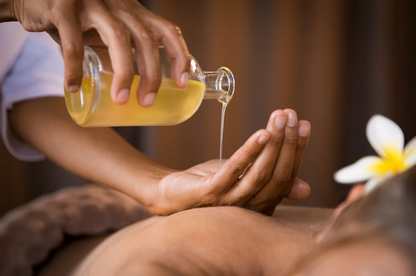 Ayurvedisches Massageöl wird in die Hände gegossen