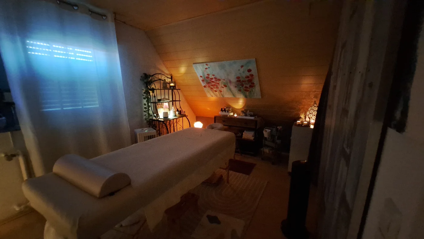Behandlungsraum mit Massageliege und warmem Licht